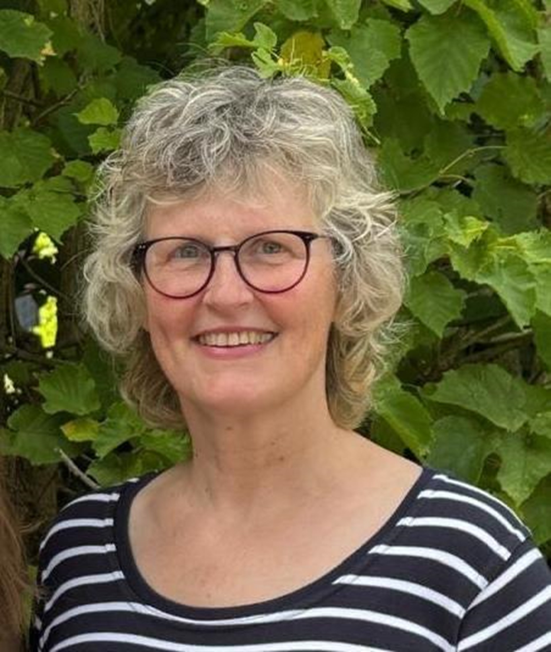 Eine Frau (Heike Riederer) mit Locken und Brille schaut in die Kamera.